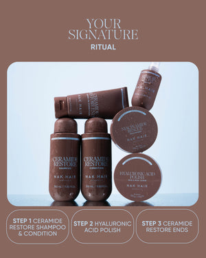 A set of brown haircare products arranged on a light blue reflective surface, with the words 'YOUR SIGNATURE RITUAL' above and three rounded text boxes below describing the steps. The products appear to be a shampoo, conditioner, and two polishes from NAK HAIR, branded with 'SIGNATURE RESTORE' and 'NAK HAIR'.