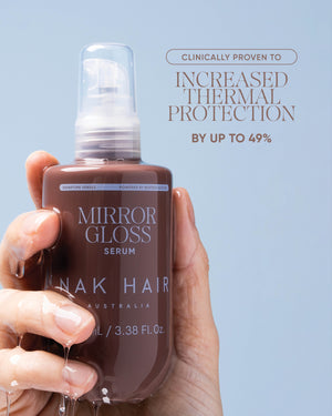 A hand holds a bottle of Mirror Gloss Serum by NAK Hair against a light blue background, with promotional text on the right stating it is clinically proven to increased thermal protection by up to 49%.